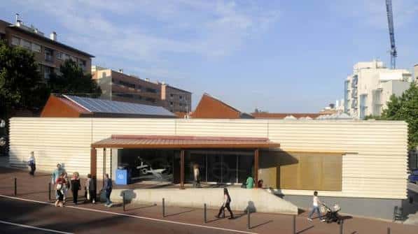 Vista exterior diurna de la Biblioteca Les Roquetes con su fachada de madera clara y techo inclinado