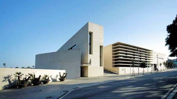 Fachada lateral del edificio con arquitectura contemporánea y vegetación en primer plano