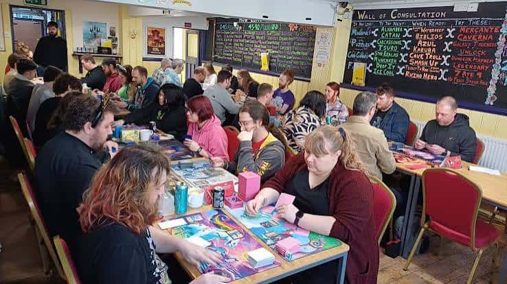 Grupo de personas jugando a juegos de mesa en mesas, ambiente social y animado