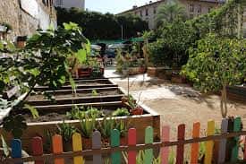 Jardín comunitario con huertos urbanos y valla de colores