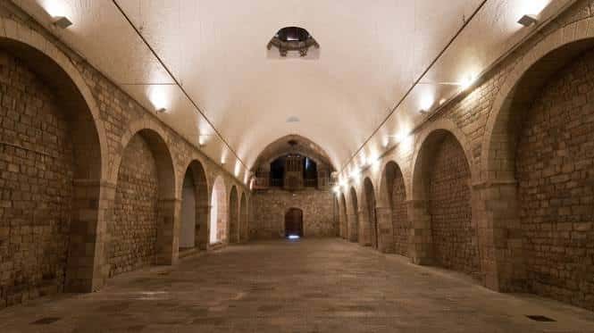 Vista interior de la sala principal con bóvedas de piedra y arcos medievales