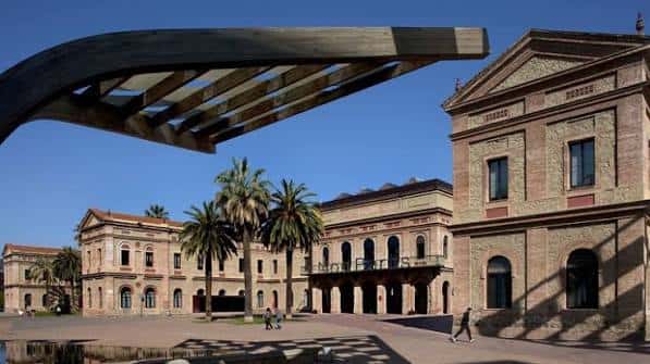 Plaza con escultura moderna y fachada neoclásica bajo cielo despejado