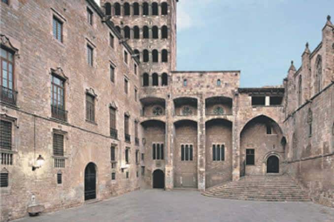 Plaza histórica con fachadas de piedra y torre gótica al fondo