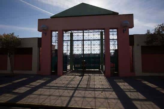 Entrada principal del complejo con portada rosa y reja metálica