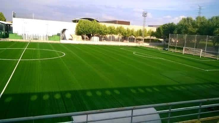 Vista panorámica del campo de fútbol con césped artificial y gradas laterales