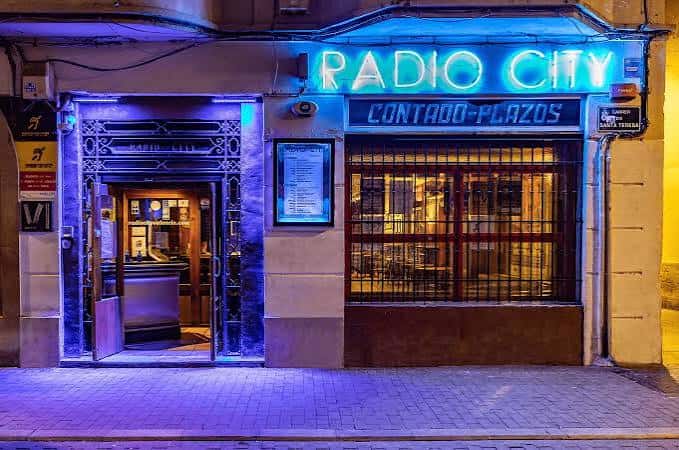 Fachada nocturna del local Radio City con neón azul
