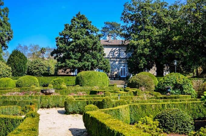 Jardines formales del Pazo con setos recortados y camino central