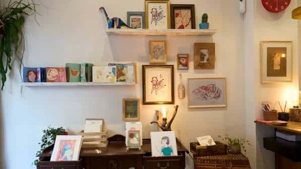 Pared decorada con cuadros, libros y objetos vintage en estanterías