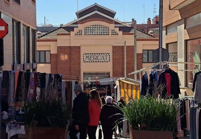 Entrada del Mercat Sagarra con puestos de ropa al aire libre y personas caminando