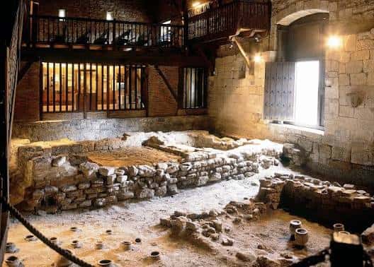 Interior del museo con ruinas romanas expuestas y estructura de madera de protección
