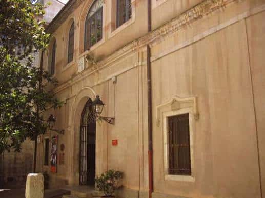Fachada exterior del Arxiu Municipal de Girona con entrada arqueada y faroles de estilo clásico