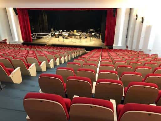 Vista general del auditorio con butacas rojas y escenario preparado