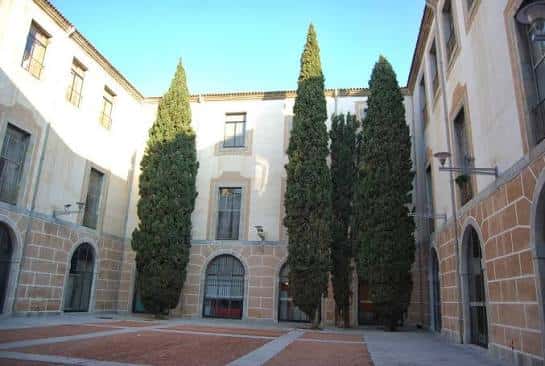 Patio interior del edificio con árboles altos y arquitectura clásica, ideal para eventos al aire libre