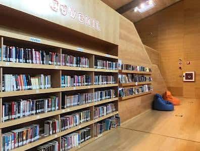 Sección infantil de la biblioteca con estanterías y zona de lectura