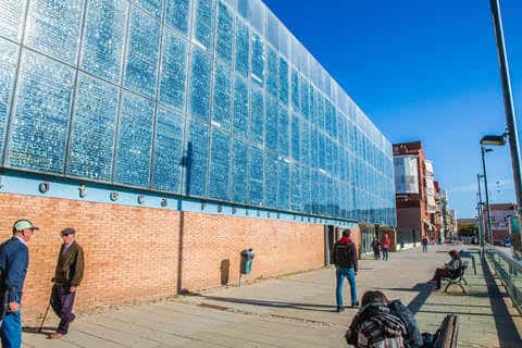 Fachada exterior de la biblioteca con pared de vidrio y ladrillo