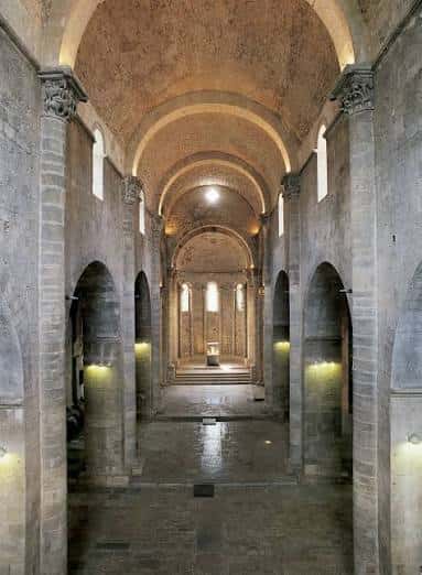 Interior de la nave principal con bóvedas de cañón y columnas de estilo románico