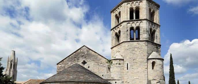 Detalle de la torre y fachada del monasterio bajo un cielo azul con nubes