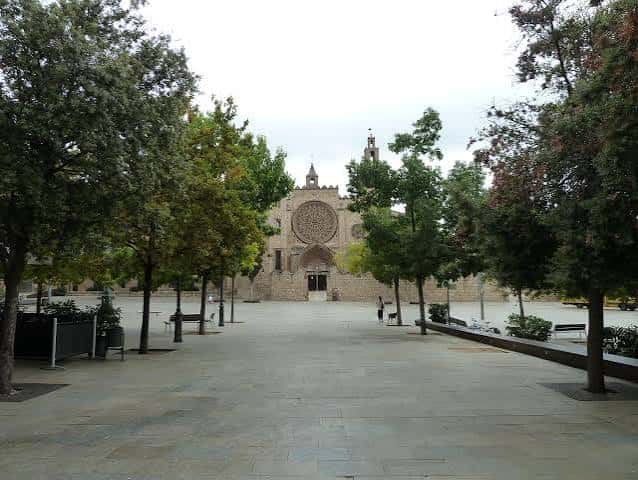 Vista actual de la Plaça Octavià con la iglesia de fondo y árboles en primer plano