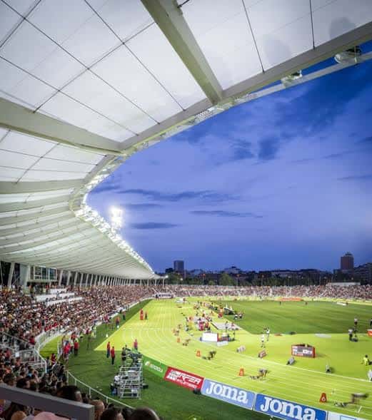 Interior del estadio durante un evento deportivo con gradas llenas y pista iluminada