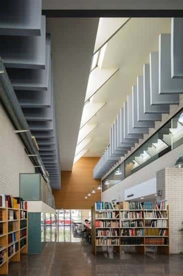 Interior del centro cívico con estanterías de biblioteca y escalera de diseño arquitectónico