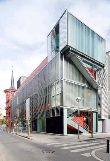 Vista moderna de la ampliación de la biblioteca con estructura de cristal y acero junto al edificio histórico