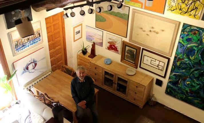 Interior de la galería con obras de arte en las paredes y una persona sentada en una mesa