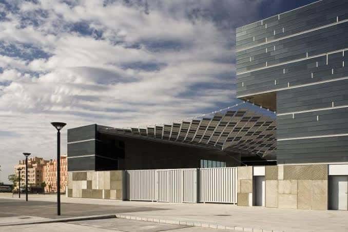 Detalle arquitectónico de la fachada lateral con estructura metálica y cielo nublado