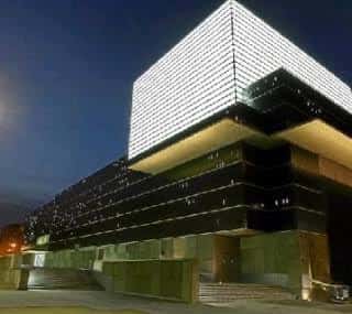 Fachada del Palacio de Congresos iluminada por la noche con efecto de luces en la torre superior