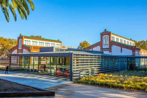 Vista exterior de la Biblioteca Antoni Comas mostrando la fachada histórica y la ampliación moderna de cristal
