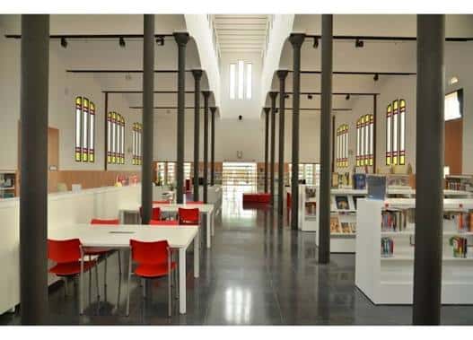 Interior del salón de lectura con columnas de hierro y grandes ventanales de colores