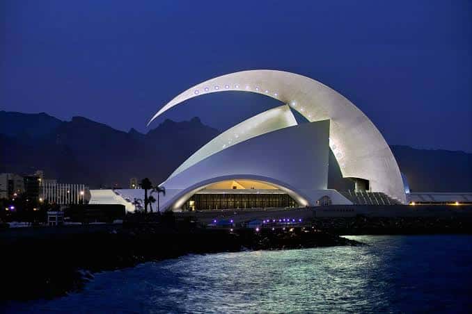 Vista nocturna del Auditorio de Tenerife con su icónica fachada curva iluminada frente al mar