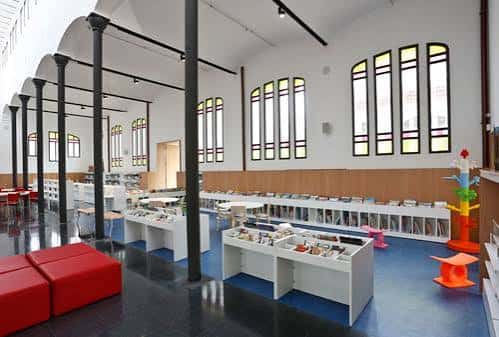 Sala de lectura infantil con estanterías bajas y mobiliario colorido