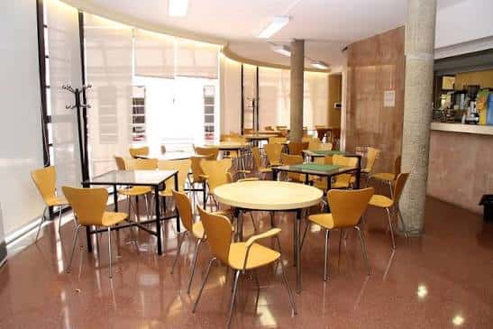Sala interior del centro con mesas y sillas amarillas, ideal para eventos sociales o reuniones