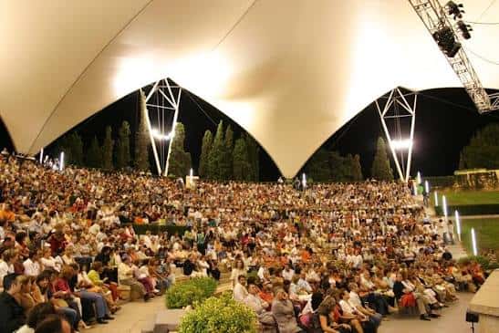 Interior del auditorio durante un evento nocturno, con el público sentado bajo la gran cubierta iluminada