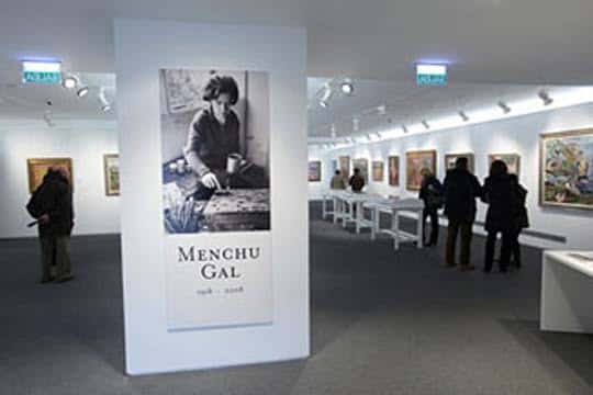 Exposición de Menchu Gal con visitantes y cartel informativo