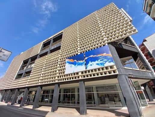 Vista exterior de la fachada moderna de la Biblioteca Mestre Martí Tauler con diseño de celosía y murales artísticos