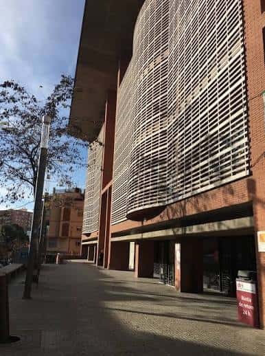 Detalle arquitectónico de la fachada curva de la biblioteca con celosía metálica bajo la luz del sol