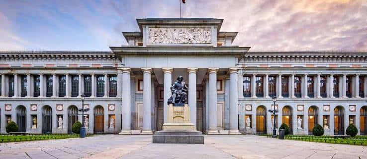 Fachada principal del Museo del Prado con columnas y estatua central al atardecer
