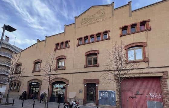 Fachada principal de la Cambra Agrària con entrada y detalles arquitectónicos bajo un cielo parcialmente nublado