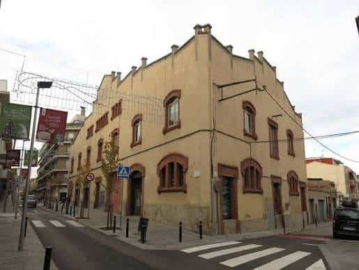 Vista exterior de la Cambra Agrària en Sant Boi de Llobregat, mostrando su fachada modernista con detalles en ladrillo y ventanas arqueadas