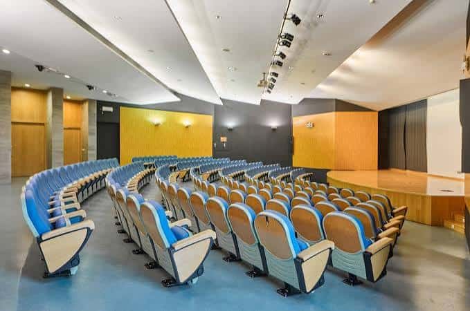 Interior del auditorio con butacas curvas y escenario amplio