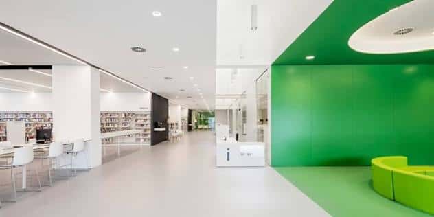 Área de lectura con sillas verdes y estanterías de libros