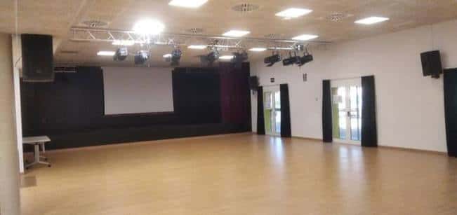Sala de eventos interior con escenario, iluminación profesional y suelo de madera