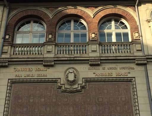 Detalle de la fachada superior con ventanas arqueadas y el nombre de la escuela en relieve