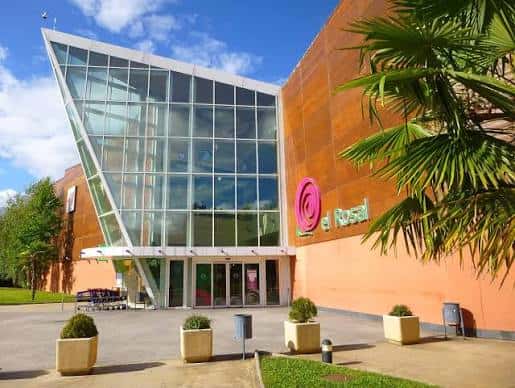 Vista exterior del Centro Comercial El Rosal con su distintiva fachada de madera y cristal