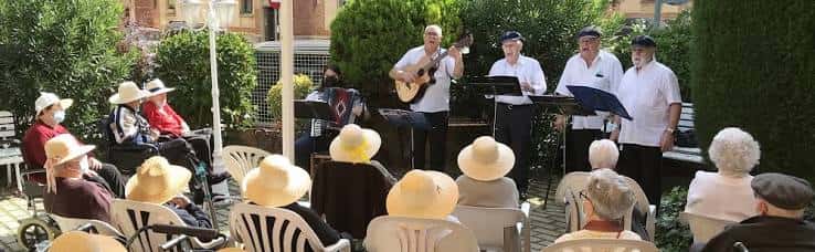 Concierto al aire libre en el patio de la residencia con músicos y residentes disfrutando