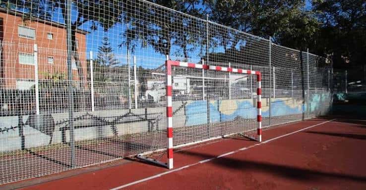 Portería de fútbol sala en pista de color rojo con valla perimetral