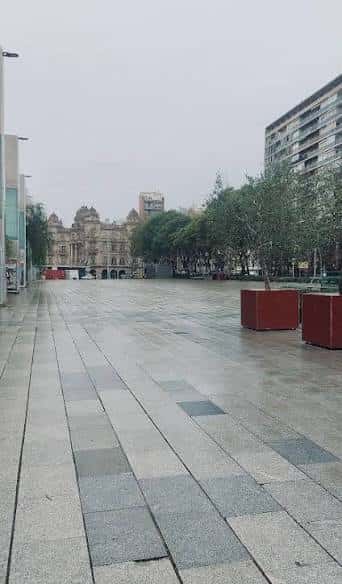 Plaza vacía con pavimento de baldosas y edificios al fondo en día nublado