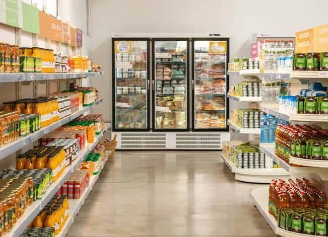 Pasillo interior de La Botiga con estanterías de productos ecológicos y neveras de cristal