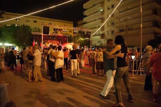Celebración nocturna en la Plaça de les Hortes con baile al aire libre y escenario iluminado, ideal para eventos comunitarios